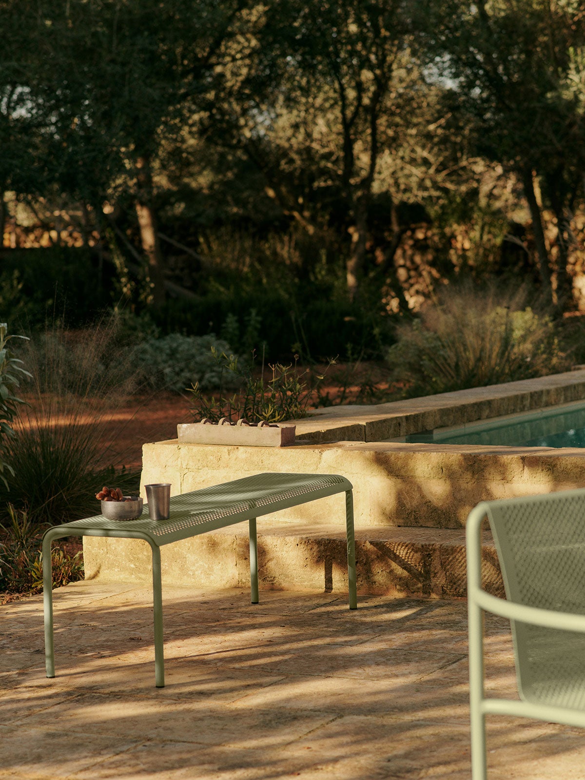 Dapple Bänk i färgen Tea Green utomhus i solnedgången