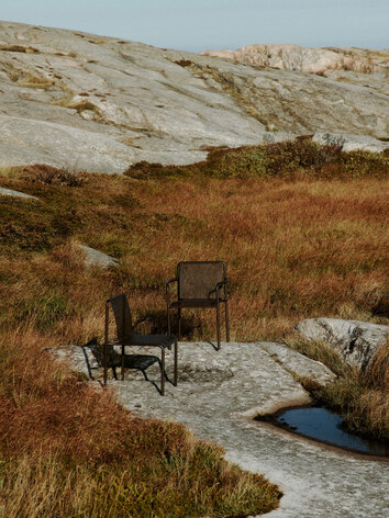 Dapple Stol och Dapple Karmstol i färgen Dark Chocolate på solig berghäll
