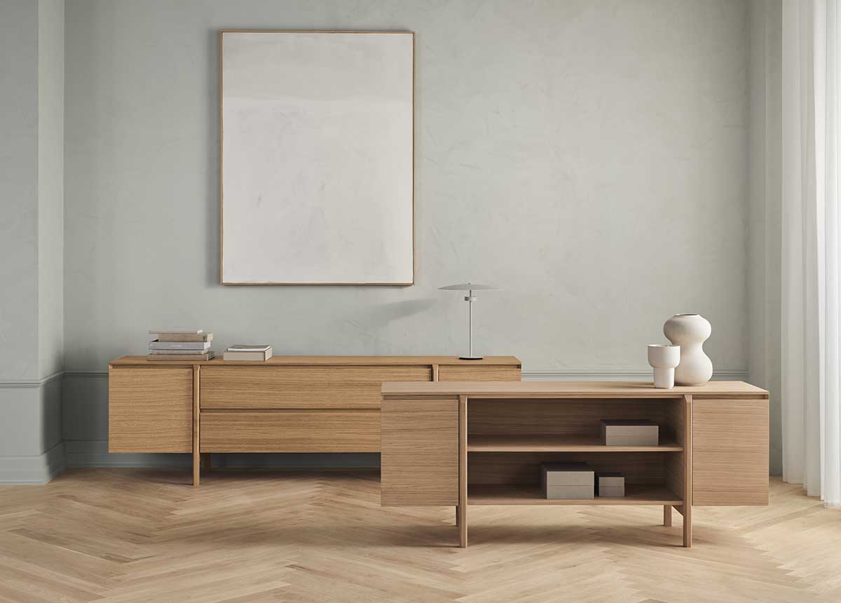 Daia Sideboard i 240 centimeter med lådor i oljad ek och 180 centimeter med hylla i vitpigmenterad ek som står i ett ljust rum med gråa väggar.