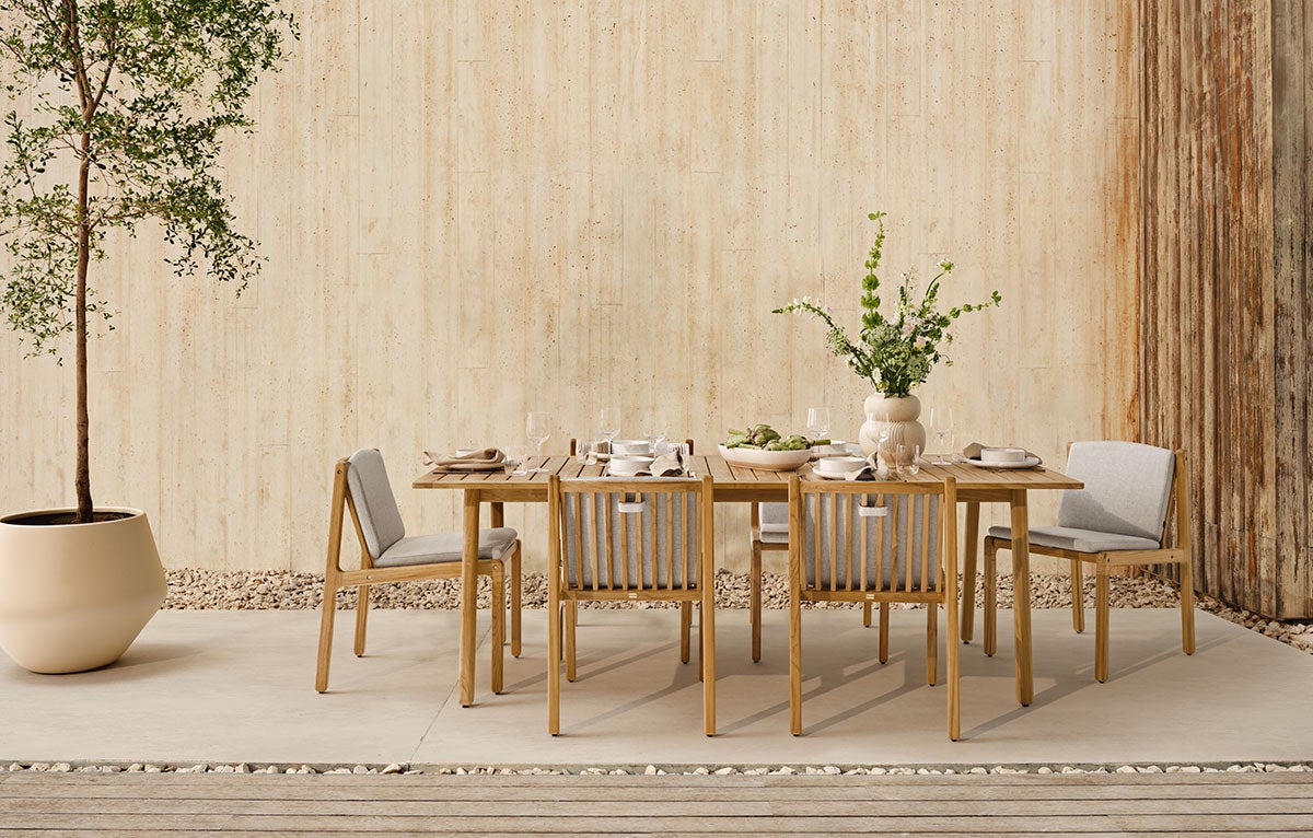 Patio trädgårdsbord och trädgårdsstolar på en uteplats. Trädgårdsbordet är dukat för middag.