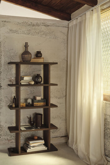 Kona 1x4 i färgen Dark Stained ståendes mot vägg fylld med dekorationer.