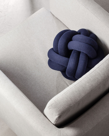 Knot Cushion Navy i grå fåtölj