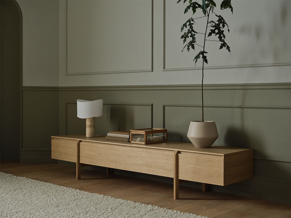 Daia Sideboard Low 240 med lådor i oljad ek dekorerat med en lampa, böcker, en glaslåda och en kruka med ett träd.