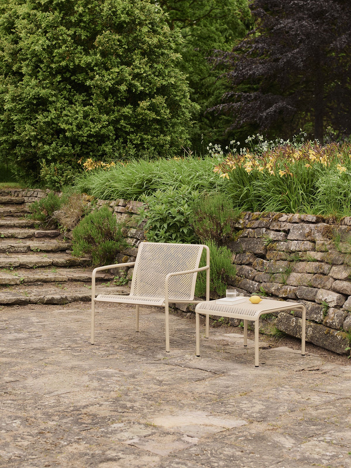 Dapple Loungestol och Dapple Loungebord 57x57 i färgen Cashmere som står på en stenig uteplats