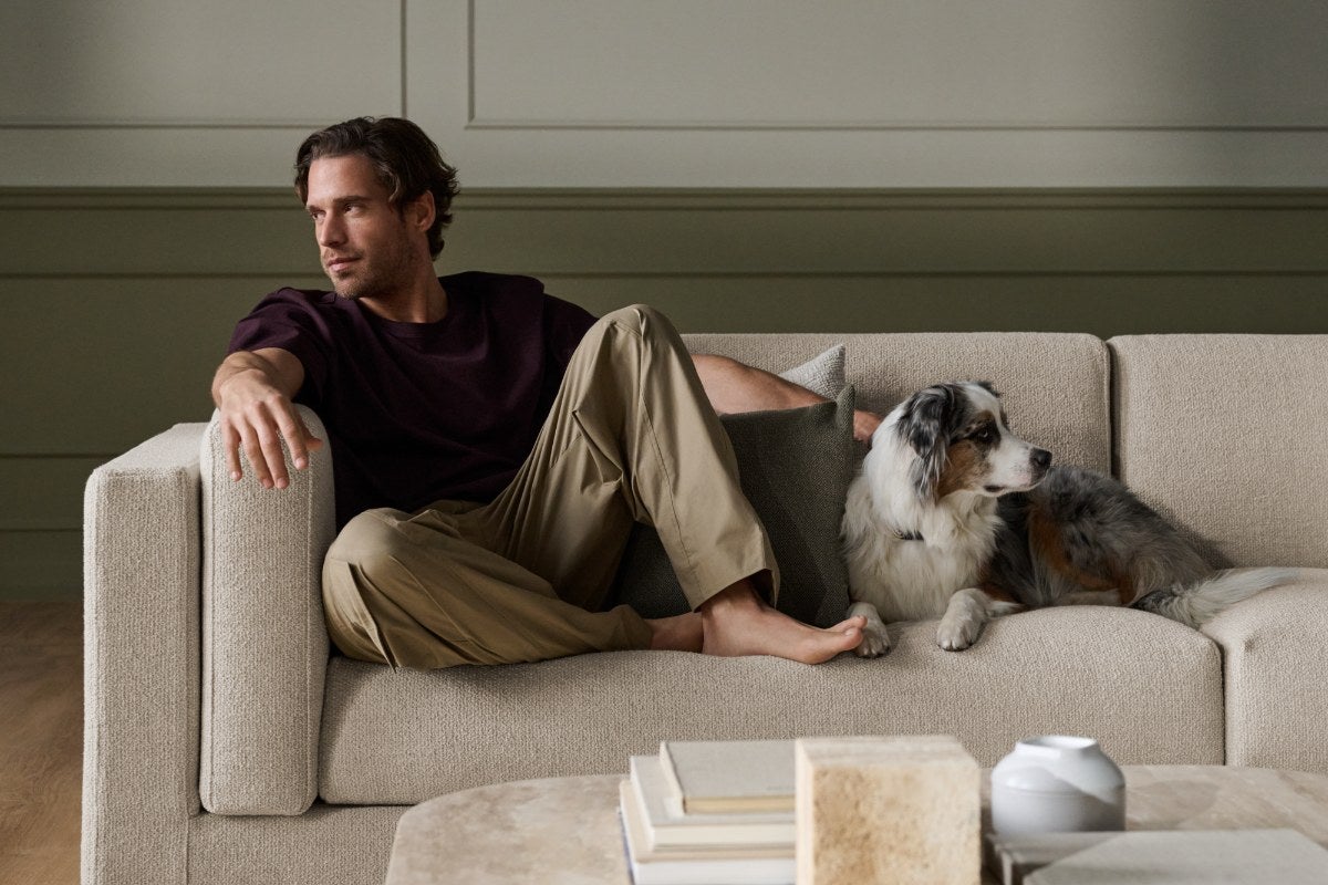 Man som vilar i en BOLIA-soffa tillsammans med sin hund
