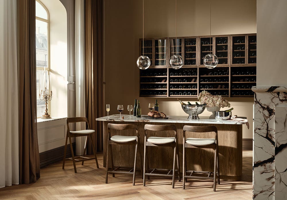Bolia-Fenri-Upholstered-Bar-Chair-H65-Dark-Oiled-Oak-Lifestyle.jpg Fenri Barstol med klädd sits kring en köksö i ett modernt kök