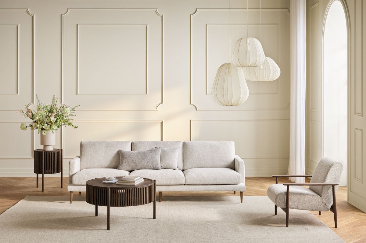 Veneda Slim Soffa 4-sits i ett ljust tyg i ett vardagsrum med moderna möbler i mörkoljat trä.