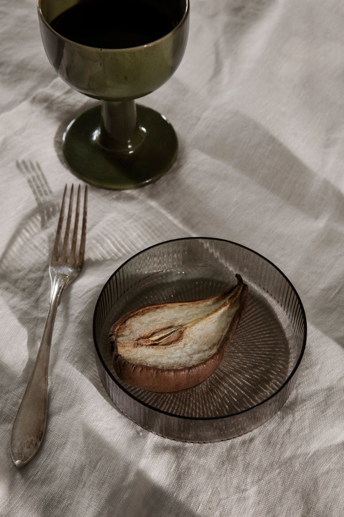 Ett päron i Ripple Skål i färgen Smoked Grey på dukat bord